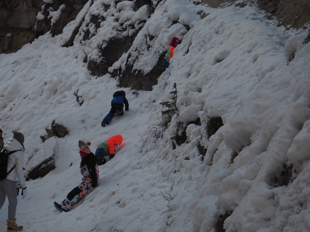 Children daringly slide down a snow/ice covered wall along Johnston Canyon, Bow Valley Parkway, Banff National Park; January 1, 2024. Photograph: Malik Merchant/Simerg Photos.